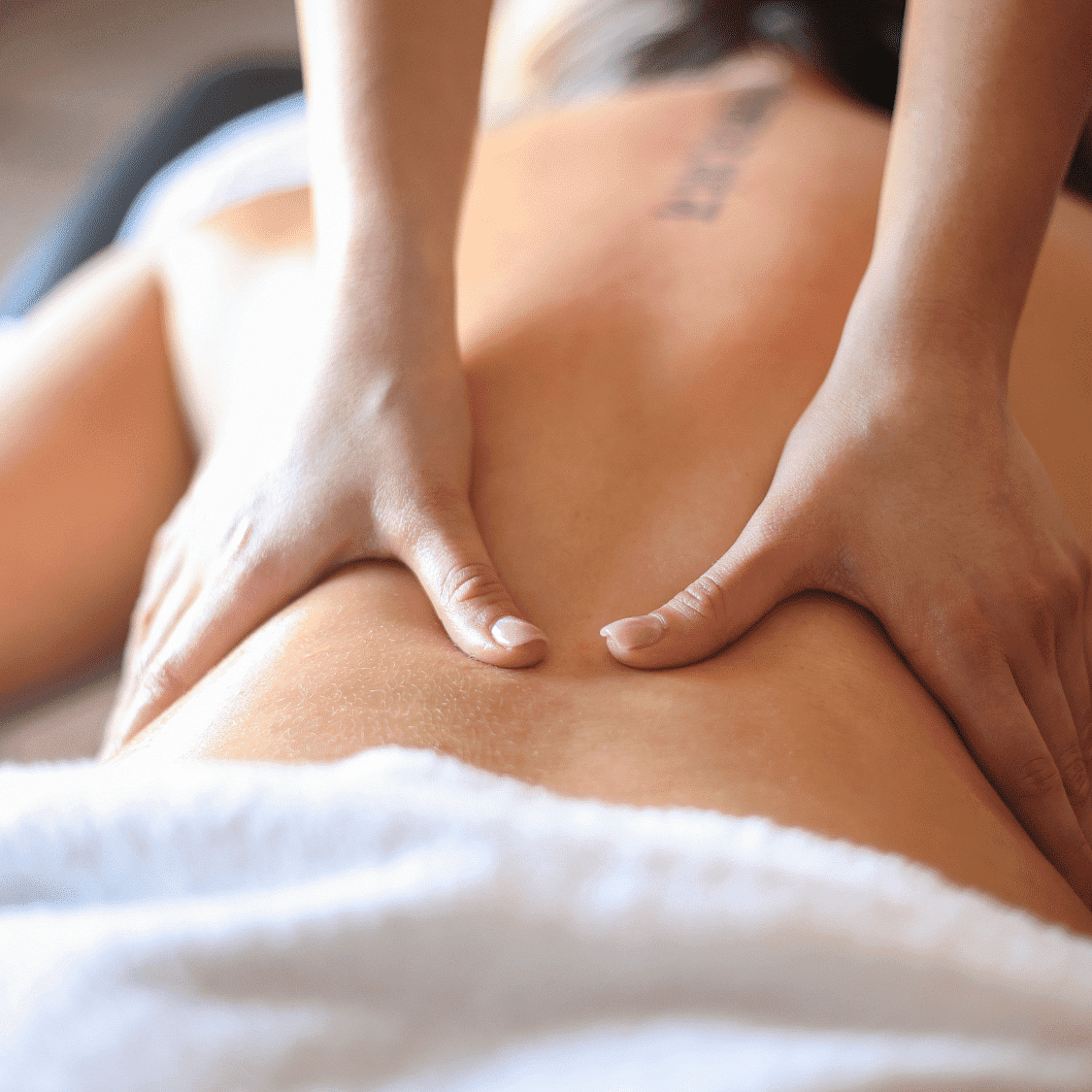 Massage therapist performing a back massage on a client.